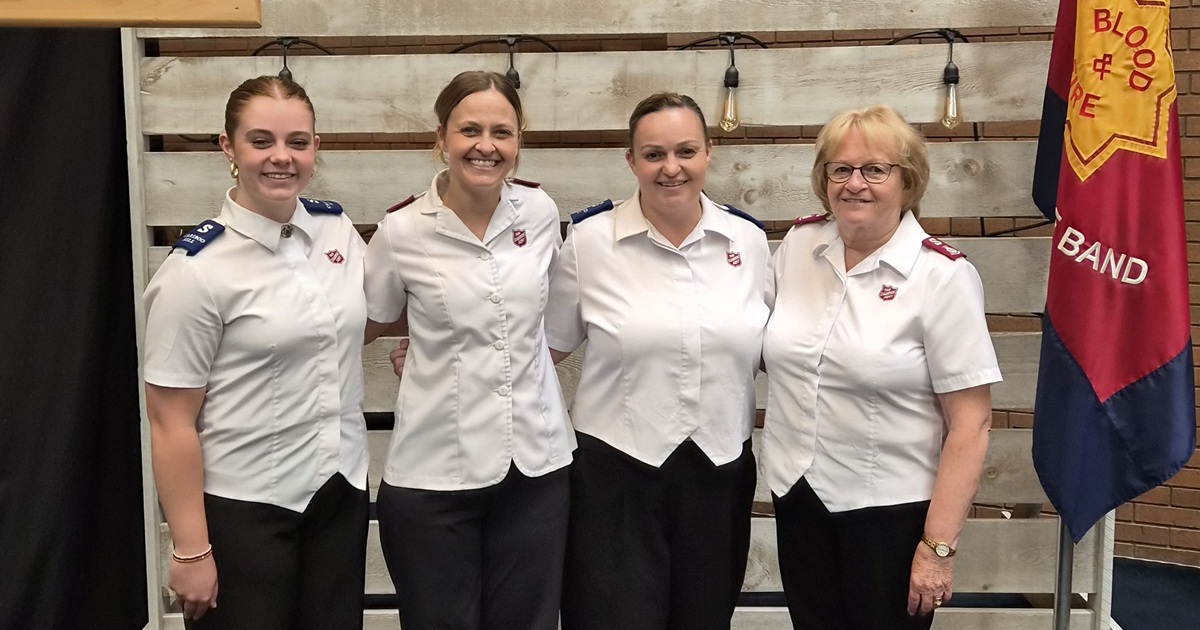 Four women of different generations stand together arm in arm